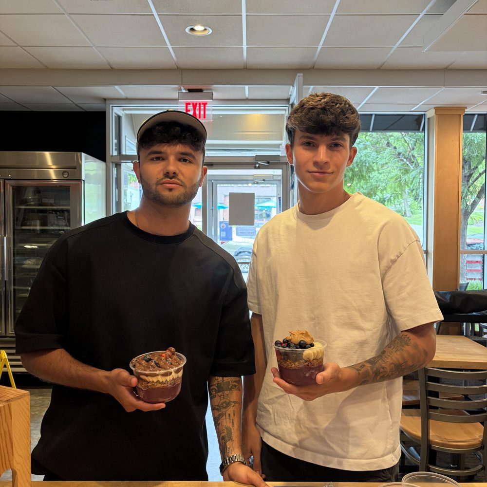 Two students holding açaí bowls at the cart