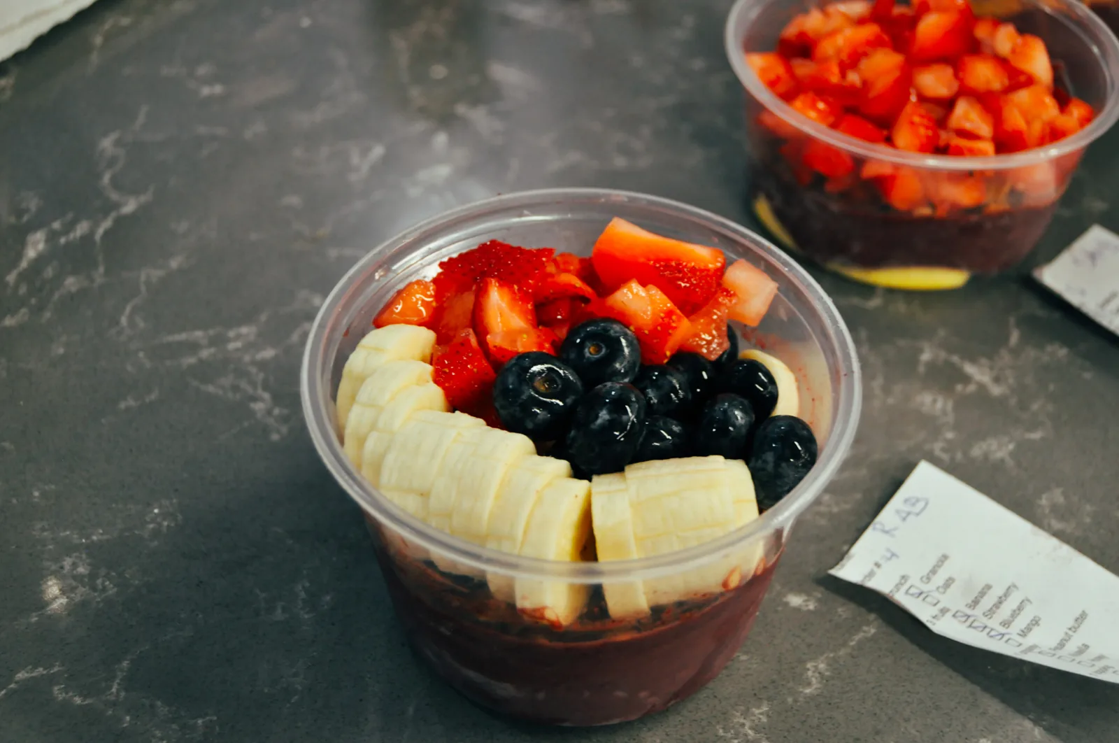 An açaí bowl topped with banana, blueberry and strawberry, built fresh at the cart